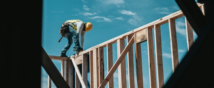 construction worker on a building site, framing a building with wooden beams