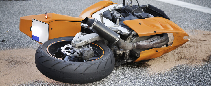 An orange motorcycle toppled over on the road
