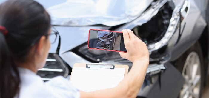 A woman takes a photo of the damage of a car after a car accident