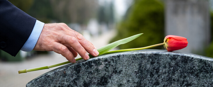 A man lays a flower on a tombstone