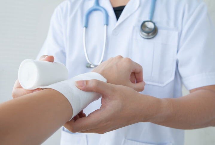 Doctor wrapping bandage over patient's arm