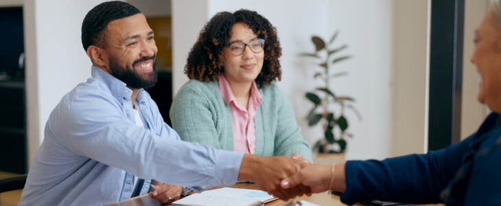 A couple shakes hands with an attorney