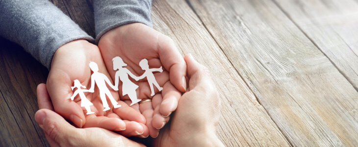 A person holds a paper fold of a family in their hand