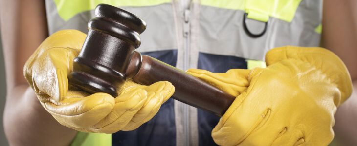 A person dressed in a construction uniform with a gavel