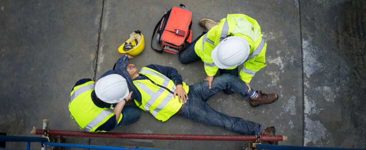 A worker lays down in pain after a construction accident
